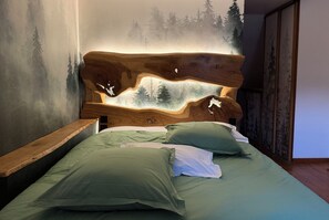 A bed with a wooden headboard featuring a painted landscape and two pillows.