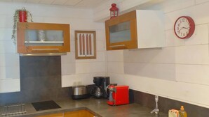 A modern kitchen with built-in appliances, a clock, and a red coffee maker.