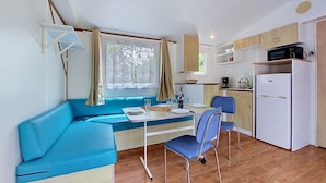 Eine kompakte Küche mit Mikrowelle, Kühlschrank und einer Essecke mit blauem Sofa und Stühlen.