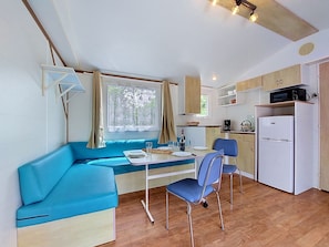Eine kompakte Küche mit Mikrowelle, Kühlschrank und einer Essecke mit blauem Sofa und Stühlen.