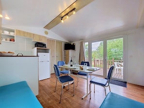 Eine kleine Küche mit Mikrowelle, Kühlschrank und einem Essbereich mit Tisch und Stühlen.