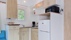 Eine kleine Küche mit Kühlschrank, Mikrowelle und Kaffeemaschine.
