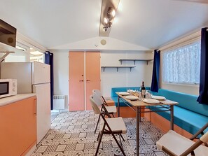 A compact kitchen with a microwave, refrigerator, and a table set for dining. - Le Kernic 2 by Interhome (Plouescat)