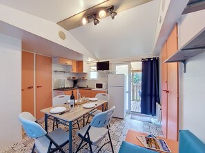 A compact kitchen with a dining table, chairs, and a refrigerator. - Le Kernic 2 by Interhome (Plouescat)