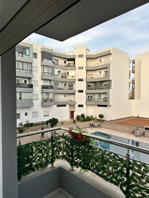 A multi-story residential building with balconies, a swimming pool, and outdoor seating. - A Relaxing Stay—Swimming Pool, Balcony, and Close to the Sea (Mohammédia)