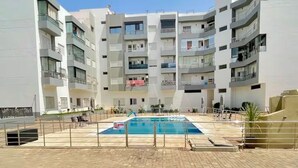 En flervåningsbostadsbyggnad med en swimmingpool i mitten.