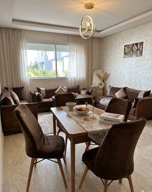 Ein modernes Wohnzimmer mit Esstisch, Sofas und einer Pendelleuchte.