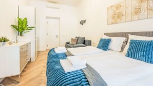 Een moderne hotelkamer met een bed, nachtkastjes, een bureau, een stoel, een potplant en een kroonluchter.