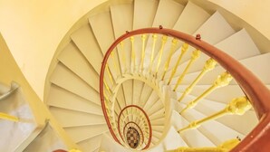 En spiraltrappa med en central pelare och gula balustrar.