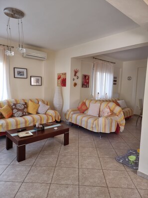 A living room with two sofas, a coffee table, and a dining table.