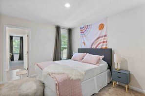 Une chambre à coucher avec un lit, des tables de chevet, une lampe et une vue sur l’extérieur.