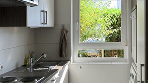 Una cocina moderna con electrodomésticos de acero inoxidable, una ventana con vistas a la vegetación y piso de baldosas.
