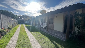 Uma trilha leva a um edifício com telhado de cerâmica, antena parabólica e uma rede.