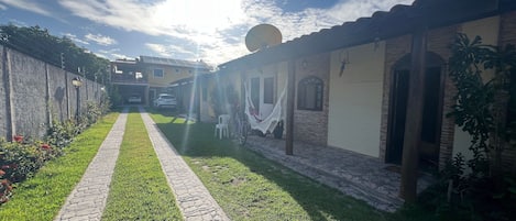 A pathway leading to a building with a tiled roof, a satellite dish, and a hammock.