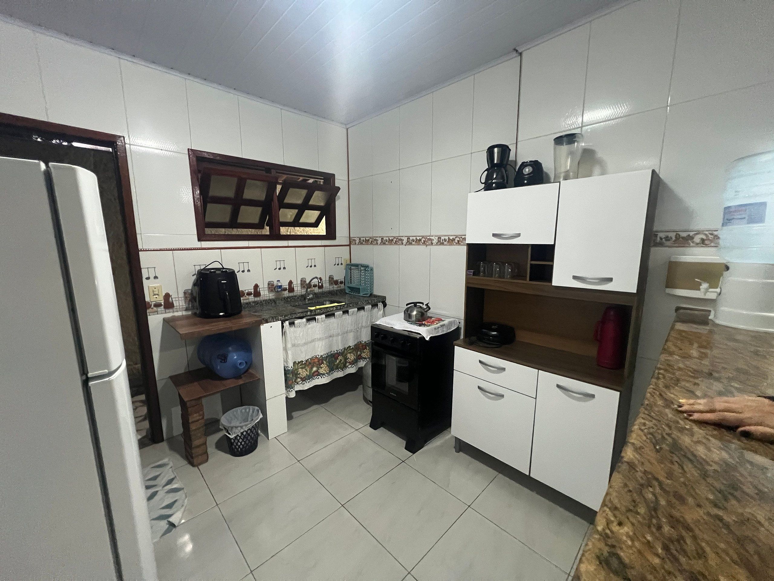 A compact kitchen with white cabinets, a black countertop, and a window above the sink.