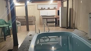 Una piscina al aire libre con zona de estar techada, una mesa y sillas.