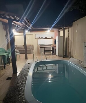 Ein Außenpool mit überdachter Sitzgelegenheit, einem Tisch und Stühlen.