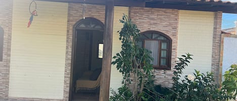 A house with a tiled roof, a door with a window, and a small garden area.