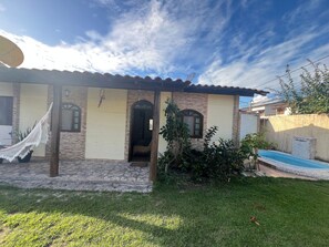 A house with a tiled roof, a hammock, a small pool, and a garden.