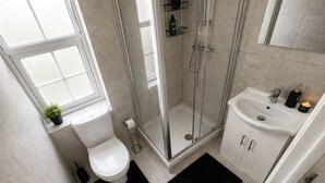 A modern bathroom with a toilet, shower, sink, and a window. - Modern Luxe Studio | Discount For Long Stays (Southall)