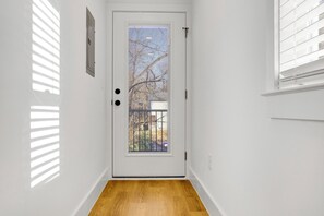 Eine weiße Tür mit Fenster, Holzboden und Blick auf einen Baum.