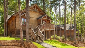 A wooden cabin with a porch and staircase, surrounded by trees. - Go to DC 250yr July 4th Celebration,  3 br Cabin at Shenandoah Crossing Resort (Gordonsville)
