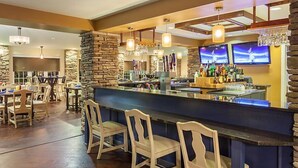 A bar area with wooden chairs, a counter with bottles, and stone walls. - Go to DC 250yr July 4th Celebration,  3 br Cabin at Shenandoah Crossing Resort (Gordonsville)