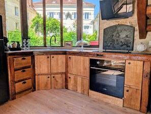 A kitchen with wooden cabinets, a built-in oven, a sink, and a view of a building through large windows.