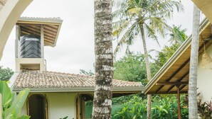 Un jardín con una palmera, un arco de ladrillo y un edificio con techo de tejas.