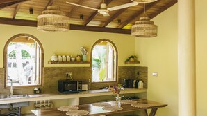 Una cocina rústica con vigas de madera, una isla grande y lámparas colgantes de mimbre.