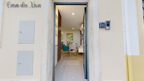 Ein Hotel Eingang mit einem Schild mit der Aufschrift 'Casa da Xaxa', einem Empfangsbereich, einem Spiegel und einer Sitzecke mit Stühlen.