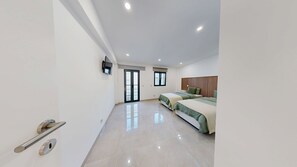 Un dormitorio moderno con dos camas, un televisor y un balcón al que se accede por una puerta corredera.