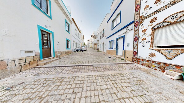 Una estrecha calle empedrada bordeada por edificios con detalles azules y azulejos decorativos.