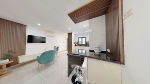 Ein modernes Wohnzimmer mit Flachbildfernseher, einem Essbereich mit türkisfarbenen Stühlen, einer Küche mit Granitarbeitsplatten und einer Wand als Holzdekor.