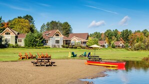 A lakeside property with a dock, picnic tables, and a row of beach chairs.