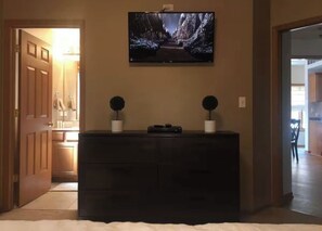 A room with a dark wooden dresser, a flat-screen TV mounted above it, and two potted plants on either side. - 2-bedroom apartment in pleasant Oak Lawn with AC comfort (Oak Lawn)
