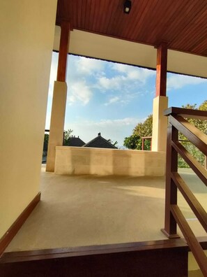 Un'area esterna riparata con ringhiera in legno, pavimento in cemento e vista su edifici sullo sfondo.
