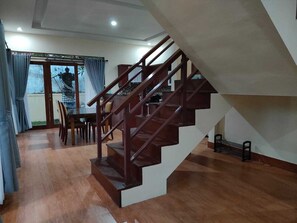 Eine Treppe führt zu einer oberen Etage, ein Essbereich mit Stühlen und einem Tisch sowie ein Blick durch eine Glastür.