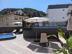 Ein Poolbereich auf dem Dach mit Liegestühlen, Sonnenschirmen und einem Schwimmbecken.