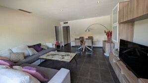 Un salon moderne comprenant un canapé, une table basse, un téléviseur et un coin repas.