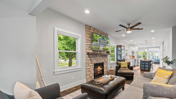 A spacious living room with a fireplace, leather sofas, and a view of the outdoors. - Walk to Lake & Downtown · 3BR Home Sleeps 8 (Lake Geneva)