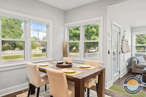 Un coin repas avec une table dressée pour quatre personnes, de grandes fenêtres et une vue sur une courClose.