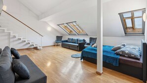 Un dormitori d'estil loft amb una escala, un sofà, un llit i velotaries.