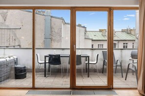 A balcony with a table and chairs, a grill, and a suitcase. - Spacious 3BR Apartment in Prague Center Apartworld (Praha)
