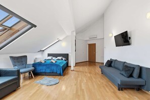 Ein modernes Schlafzimmer im Loft-Stil mit Dachfenster, einem großen Bett, einer Couch und einem Fernseher.