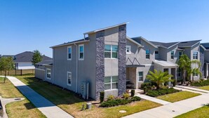 A modern two-story residential building with a stone facade, multiple windows, and a well-maintained lawn. - 5BR ChampionsGate Home with Pool & Water Park (Championsgate)