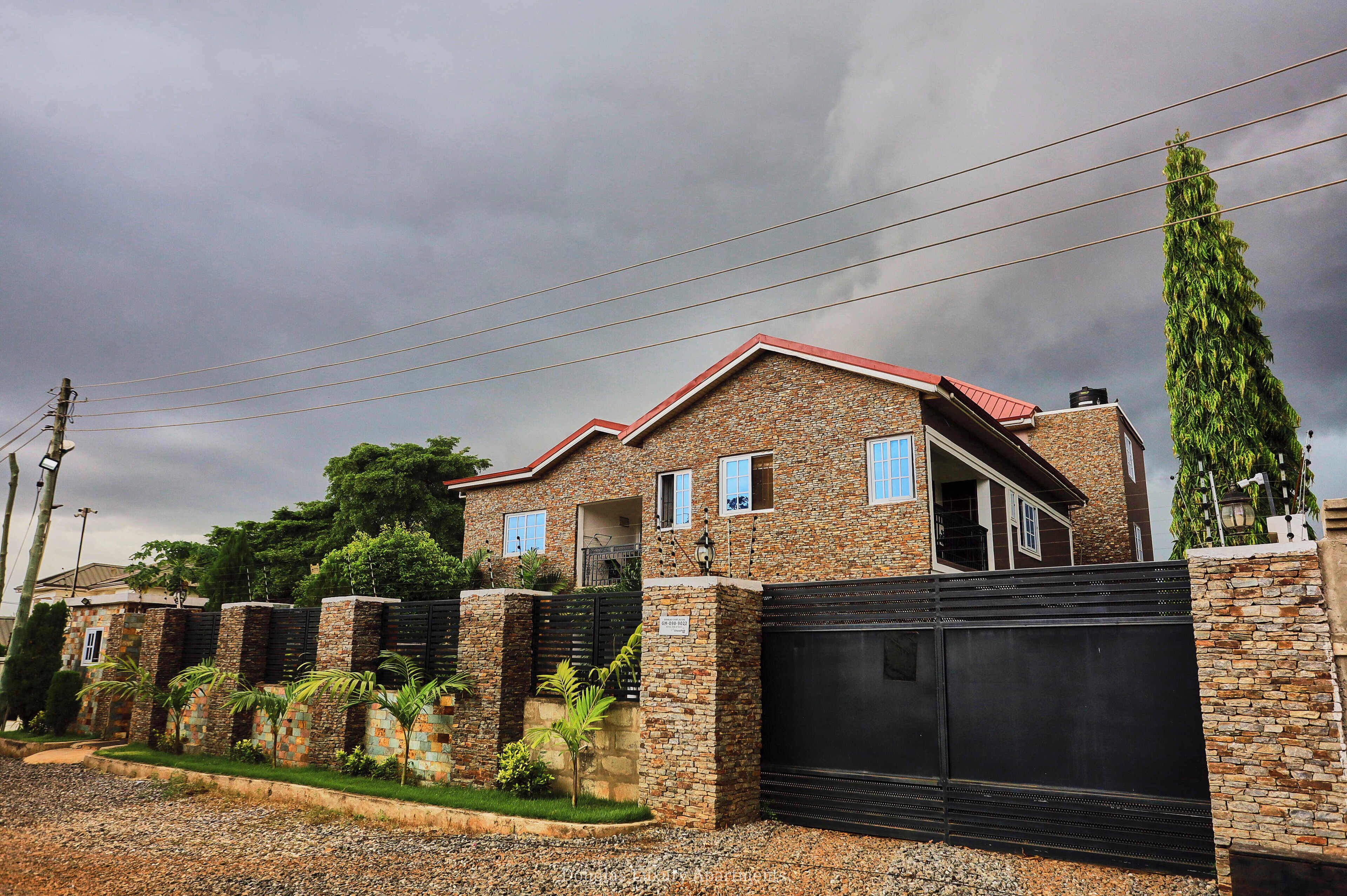 A house with a brick exterior, a red roof, and a black gate.