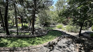 A landscaped garden with a pond, surrounded by trees and stone pathways. - Stonewater Cove 1br BLOCK (Shell Knob)