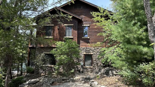 A rustic wooden cabin with a stone foundation, surrounded by dense forest. - Stonewater 2br BLOCK (Shell Knob)