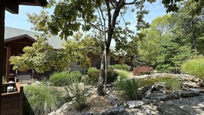 A garden with a wooden deck, a stone wall, and various plants. - Stonewater 2br BLOCK (Shell Knob)